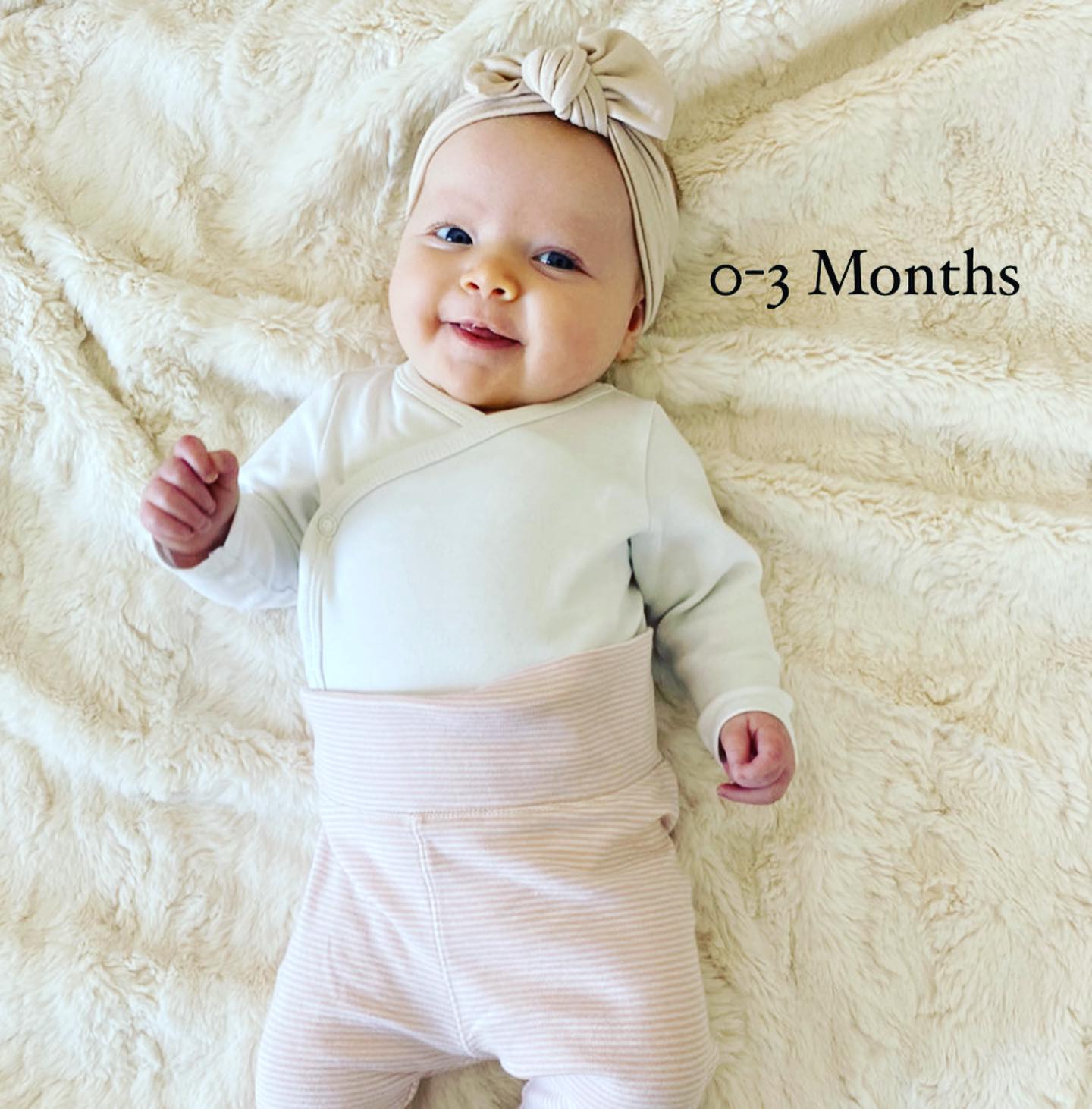 Smiling baby lying on a soft blanket, from a 0–3 month milestone series