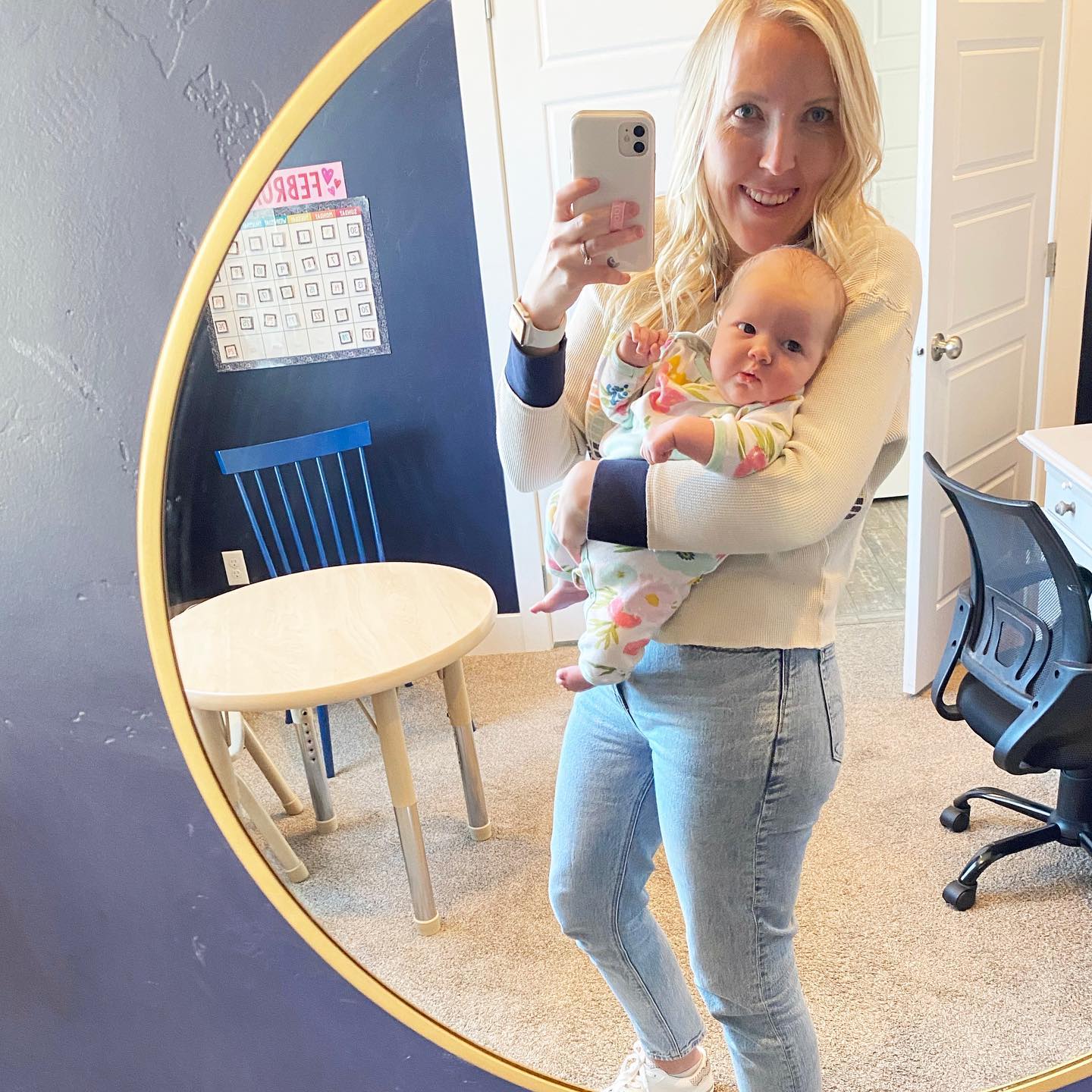 The Hansen Home Speech therapist smiling in her home therapy room, holding her newborn.