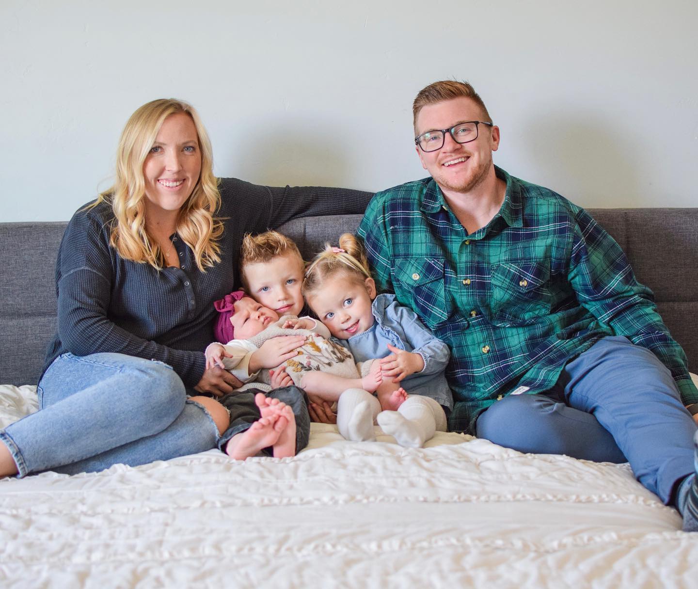 The Hansen family &mdash; parents with their three young children on a couch, warm and connected.
